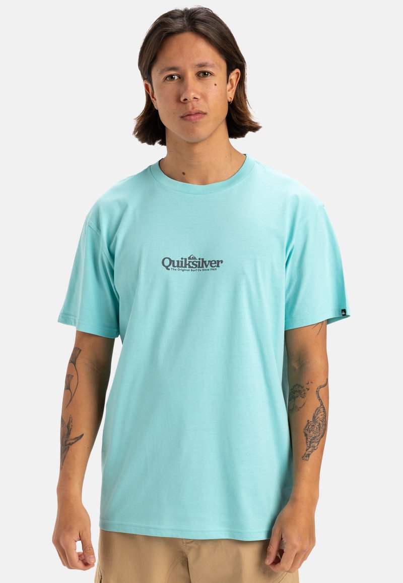 Camiseta de algodón de manga corta en color turquesa con un corte relajado. Presenta un estampado del logo en marrón en el pecho y un diseño de cuello redondo.