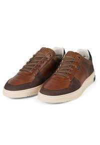 Sneakers in pelle marrone e tessuto marrone texture con suole crema, dotati di lacci e dettagli neri sul tallone. Modelli visibili sulla superficie.