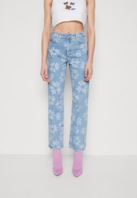 Lichtblauwe denim jeans met een bloemenprint. Gecombineerd met lichtroze, gestructureerde enkellaarzen met hak en een witte cropped top.