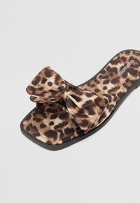 Sandály s leopardím vzorem a mašlí; měkký textilní materiál, čtveratá špička a černá gumová podešev.