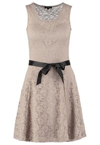 Robe en dentelle beige sans manches avec motif floral et un ruban en satin noir noué en nœud à la taille.