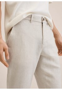 Jasnoszare lniane spodnie o eleganckim kroju, z zapięciem na guziki, przednimi kieszeniami i prostymi nogawkami. Miękka tekstura, minimalne zagniecenia.