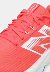 Bright coral running shoe with white "N" logo, patterned upper, matching laces, and "FuelCell Propel" label on tongue.