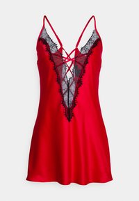 Red satin slip dress featuring a black lace panel with frayed edges and a crisscross design at the neckline. Slim adjustable straps.