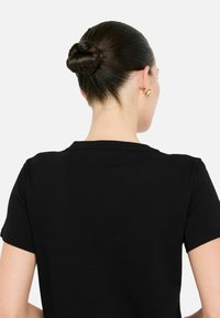 Sort T-shirt med korte ærmer, rund halsudskæring, glat tekstur, tætsiddende design og en subtil kant, båret af en person set fra ryggen.
