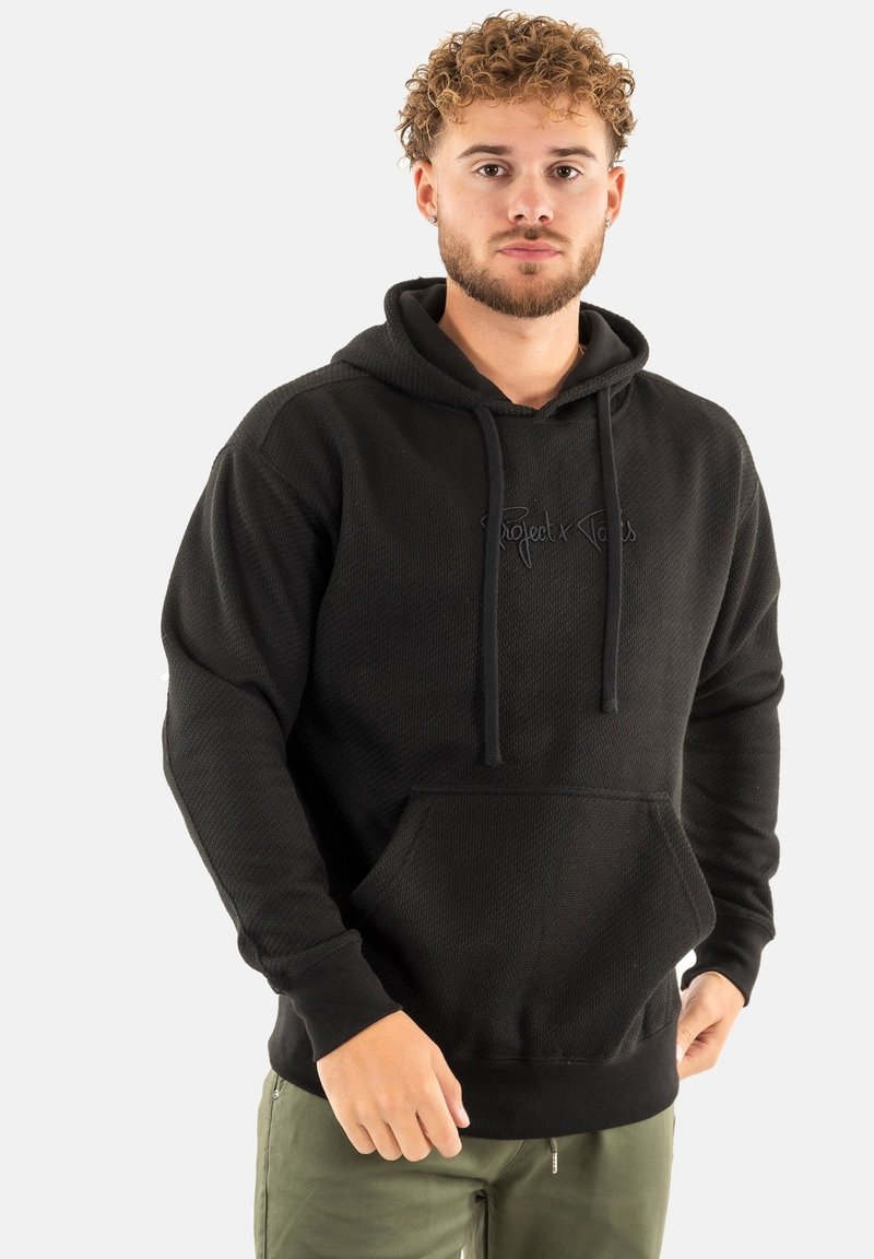 Felpa nera con superficie testurizzata, tasca frontale e cappuccio con cordini. Presenta il logo "Project Vibes" in stampa scura sul petto.
