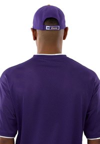 Personne vue de dos portant un maillot de sport en maille violette et une casquette violette avec le logo "Vikings" sur la sangle arrière.