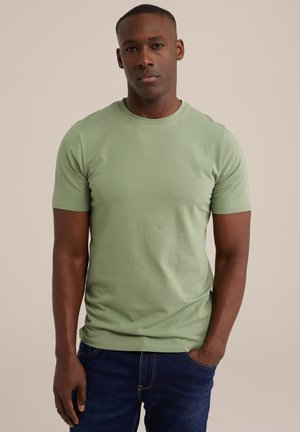 Green cotton t-shirt with a crew neck and short sleeves, featuring a fitted design and smooth texture, worn with dark blue jeans.