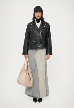 Μαύρο δερμάτινο μπουφάν μοτοσικλετιστή με ασημένιες λεπτομέρειες, συνδυασμένο με δίχρωμη φούστα από τζιν. Κρατάει μπεζ τσάντα ώμου από σουέντ. Μαύρες μπότες με τακούνι.