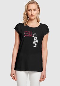Juoda trumpa rankovė t-shirt su mergaitės, laikomos kibirą, grafika, tekstu "Niekada nesisiūlys per jaunas svajoti DIDELIEM" rožine spalva.