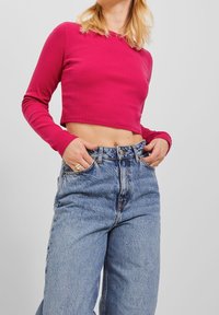 Tajt ribbad crop top i livlig fuchsia, kombinerad med högmidjade ljusa denimjeans med avslappnad passform och subtila urtvättning.