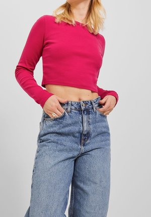 Top court ajusté en ribbed fuchsia vif, associé à un jean en denim clair taille haute avec une coupe décontractée et un léger dégradé.