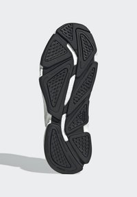 Suela de zapato de goma negra con patrones en zigzag texturizados, que cuenta con una media suela blanca y detalle del logo estampado. Diseño robusto para una buena tracción.
