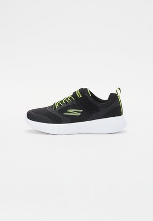 Zwarte sportieve schoen met een bovenwerk van mesh, groene accenten en veters. Heeft een witte zool en een trekband aan de hak voor gemakkelijke instap.