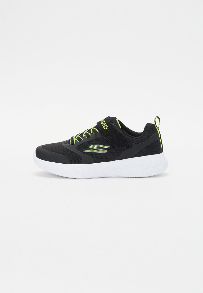Zapatilla deportiva negra con parte superior de malla, acentos y cordones verdes. Cuenta con una suela blanca y una lengüeta en el talón para facilitar su uso.