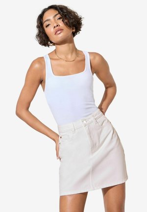 Valge tops ruudukujulise kaelusega, millele on sobitatud heledast beezist denim mini-seelik, millel on ees taskud ja diskreetne õmblusdetail.