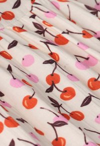 Baumwollstoff mit einem Muster aus Kirschen und pinken Beeren auf einem hellen Hintergrund, mit glatter Textur und plissiertem Design.