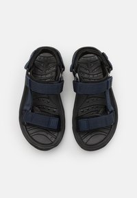 Laivastonsiniset sandaalit, joissa on kaksi säädettävää tarranauhaa. Teksturoitu musta kumipohja, jossa on kohotettuja kuvioita pitävyyden ja mukavuuden takaamiseksi. Kevyt rakenne.