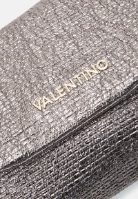 Szara teksturowana torebka kopertówka o pomarszczonym wykończeniu, z akcentem złotego logo "Valentino". Zamek błyskawiczny wzdłuż krawędzi.