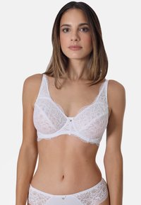 White lace bra featuring floral patterns, transparent cups, and a decorative center bow. Adjustable straps and smooth edges enhance comfort.