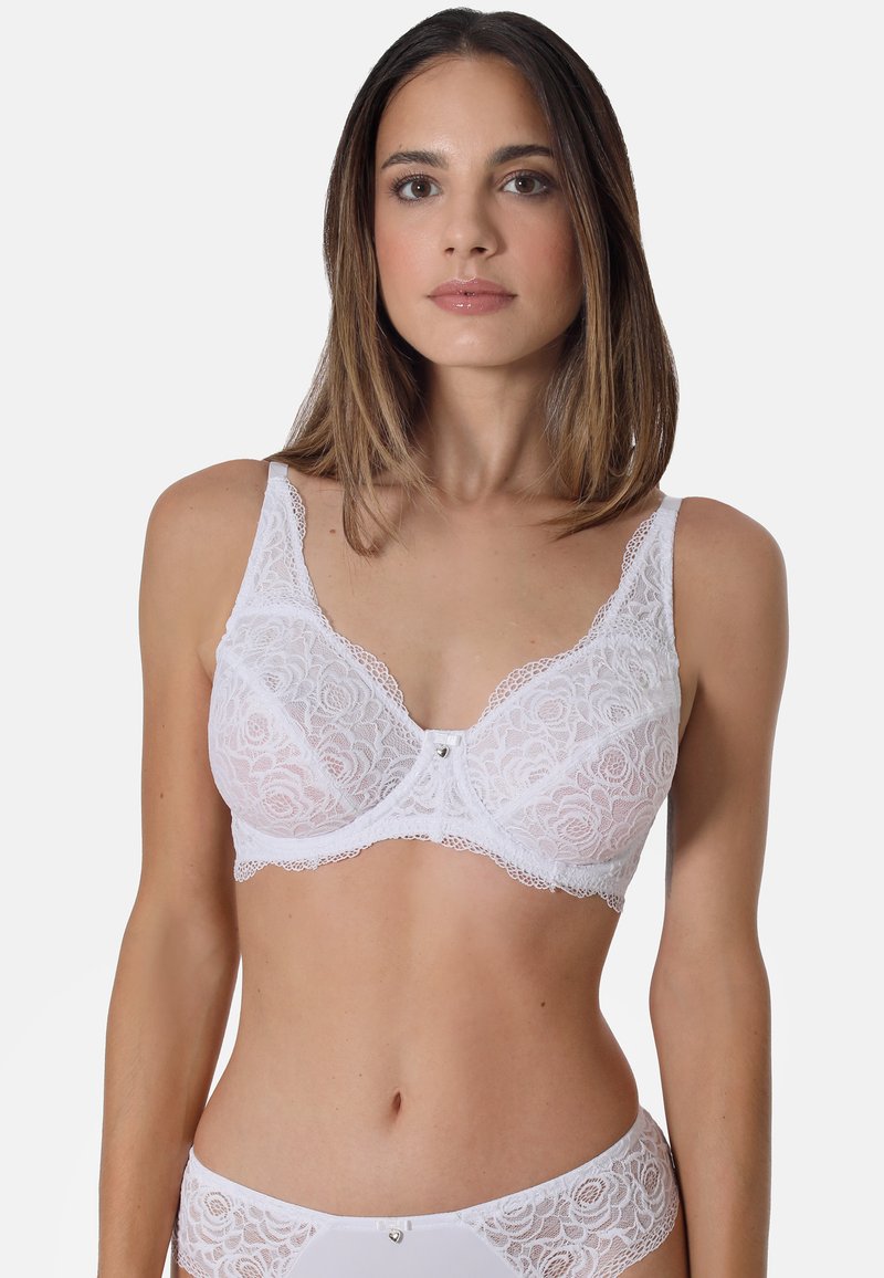 White lace bra featuring floral patterns, transparent cups, and a decorative center bow. Adjustable straps and smooth edges enhance comfort.