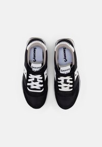 Zwarte sneakers met witte accenten, van suède en mesh materiaal, met witte veters en branding op de tong en zijpanelen.