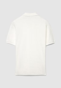 Polo blanc avec un motif en losange texturé, manches courtes et col à revers. Design simple avec une finition soignée et aucun logo visible.