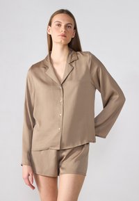 Beiges Satin-Pajama-Set bestehend aus einem langärmeligen Hemd mit Knopfleiste und Schalkragen sowie passenden Shorts mit elastischem Bund.