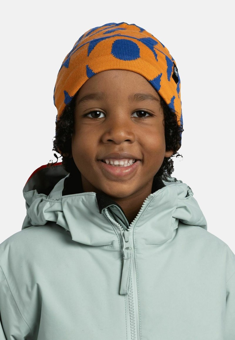 Orange beanie with blue patterns, made of knit material. Worn with a light green, zippered, hooded jacket.
