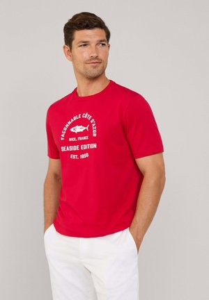 Camiseta de algodón roja con mangas cortas, que presenta un estampado gráfico que incluye "Edición de Playa" y un icono de pez en texto blanco.