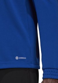 Electric blue atletisch shirt met lange mouwen, van textuurstof, met nauwsluitende manchetten en een witte "AEROREADY" logo op de zoom.
