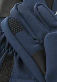 Gants bleu marine en tissu doux, avec une prise texturée sur la paume et des accents noirs aux poignets, avec un design élégant et profilé.