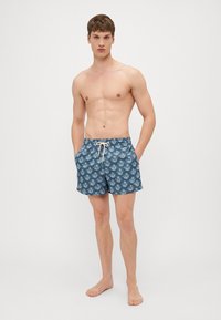 Herren Badehosen in Dunkelblau mit einem weißen Musterdesign. Sie verfügen über einen elastischen Bund und einen Zugverschluss sowie über Taschen vorne.