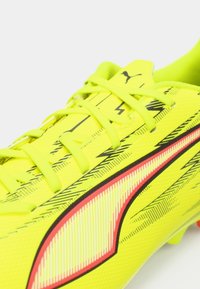 Bright yellow soccer cleat with a textured surface, featuring black and red accents, thin laces, and a distinctive PUMA logo on the side.