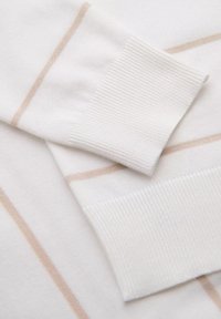 Valkoinen villapaita, jossa on vaaleanbeigeitä vaakaraitoja, varustettuna ribbaamalla viimeistellyillä hihansuilla. Smygys odotushyvä rakenne pehmeää kangasta ja siistejä ompelutietoja.