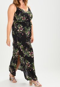 Mustakukkainen maksimekko vihreillä ja vaaleanpunaisilla kukkakuoseilla, jossa on V-pääntie, säädettävät hihnat ja solmittava vyötärö.