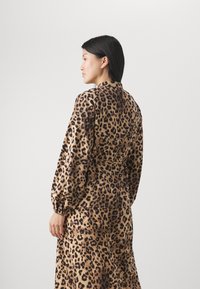 Kjole med leopardmønster, lange ermer, belted midje og mykt stoff. Har rund halsringning og elastiske mansjetter.