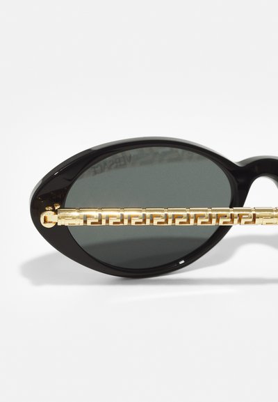 Svarta ovala solglasögon med mörka linser, med en texturerad guld kedjedesign på bågarna för extra detaljer.