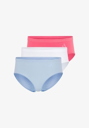 Vrouw staat blootsvoets, draagt een lichtblauwe naadloze sportbeha en hoge taille ondergoed tegen een effen witte achtergrond.