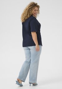Mörkblå kortärmad t-shirt i kombination med ljusblå raka jeans, med en avslappnad passform och mjuk textur. Klackade mules fulländar looken.