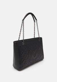 Czarna prostokątna torba na ramię z pikowanym przednim panelem, który ma wytłoczone logo "M" oraz podwójne ramiączka w formie łańcuszka.