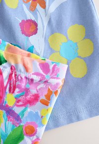 Rövid ujjú pamut ingek virágmintákkal; az egyik világoskék absztrakt virágokkal, a másik élénk, több színű virágokkal díszítve.