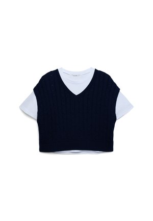 Maglione corto senza maniche in maglia blu navy con scollo a V indossato sopra una T-shirt bianca a maniche corte, caratterizzato da un motivo a trecce e orlo a costine.