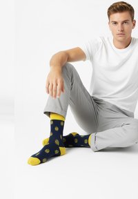 Calcetines azul marino con detalles amarillos, con un patrón repetitivo de diseños de olas, hechos de un material suave.