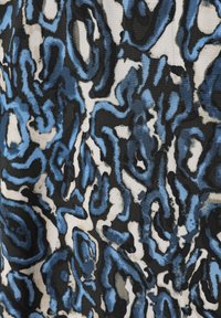 Tessuto astratto con un motivo di forme blu e nere che si intrecciano su uno sfondo bianco, con un aspetto testurizzato.