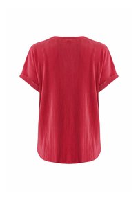 Červený žebrovaný top s krátkým rukávem, kulatým výstřihem a volným střihem. Obsahuje strukturovaný povrch a boční ohrnuté manžety.