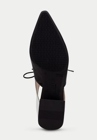 Chaussure à talon haut en noir et blanc avec une semelle en caoutchouc texturé, design élégant et laçage décoratif sur les côtés.