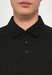 Čierna polo košeľa s textúrovaným diamantovým vzorom, s klasickým golierom, trojčlánkovým zapínaním a čiernymi gombíkmi.