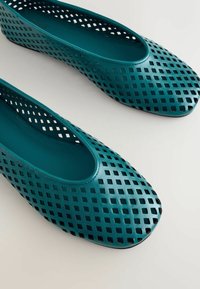 Ballerines synthétiques perforées couleur sarcelle, à bout rond et côtés ouverts. Dotées d'une doublure intérieure lisse et d'une semelle plate.