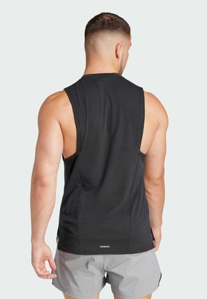Débardeur de sport noir sans manches en tissu lisse avec un ourlet arrondi et des fentes sur les côtés ; présente le texte "AEROREADY" au bas.